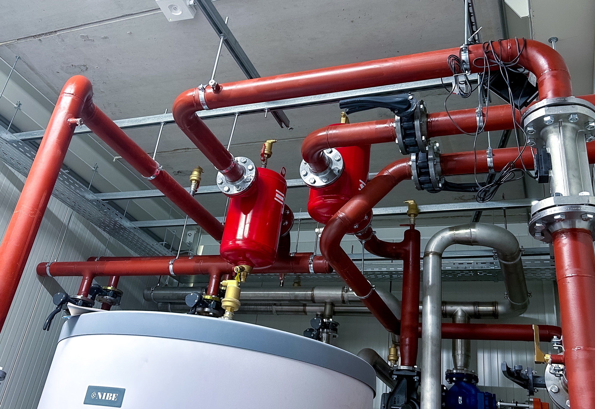 Rode verwarmingsleidingen met appendages in een technische ruimte